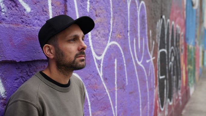 Magician dynamo wearing baseball cap leaning against graffiti wall