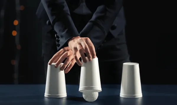Magician performing cups and balls shot in a well lit studio 