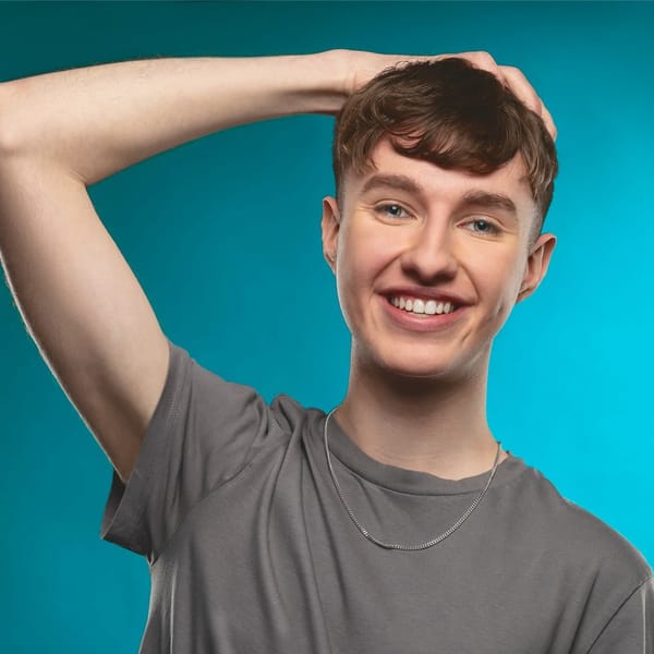 Magician Luke Oseland against a blue backdrop posing