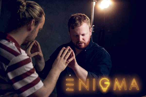 Christian Grace Enigma promo shot touching fingers with logo over the image