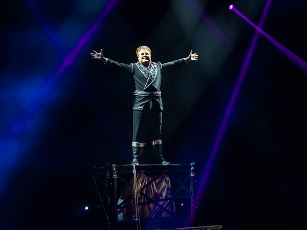 Magician Richard Young standing on illusion on stage 