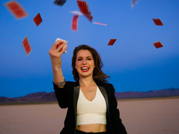 Magician Jen Kramer smiles in the desert as she springs cards