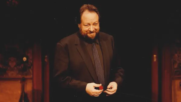 Magician Ricky Jay stands in front of classic magic props including the famous cups and balls