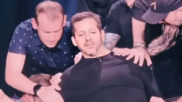 David Blaine in pain on stage floor surrounded by doctors with a dislocated shoulder